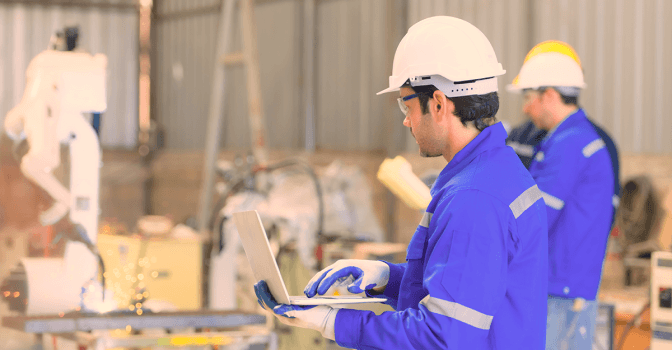 Photo of a manufacturing company with a worker holding a laptop